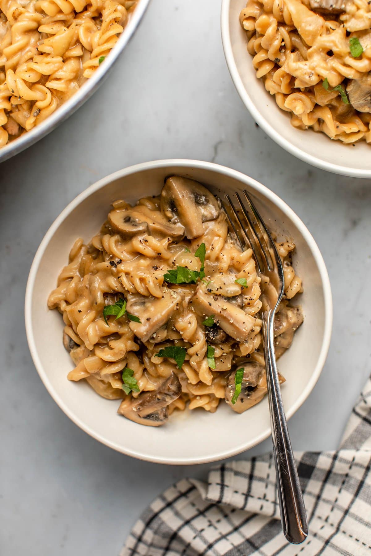 bowl of mushroom stroganoff with fresh parsley and fork on stone background