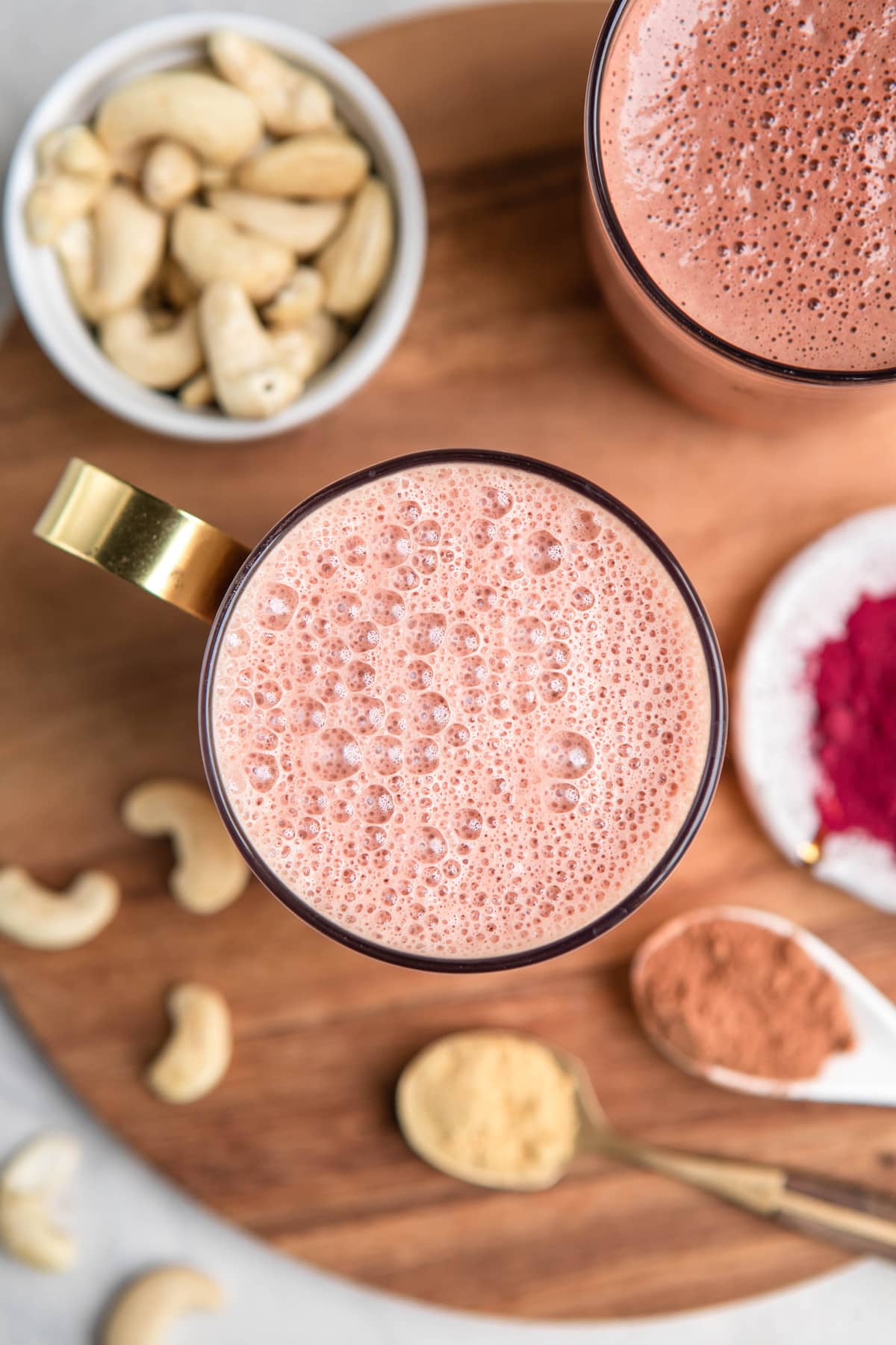 frothy pink beet latte in glass mug with gold handle