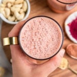 frothy pink beet latte in glass mug with gold handle