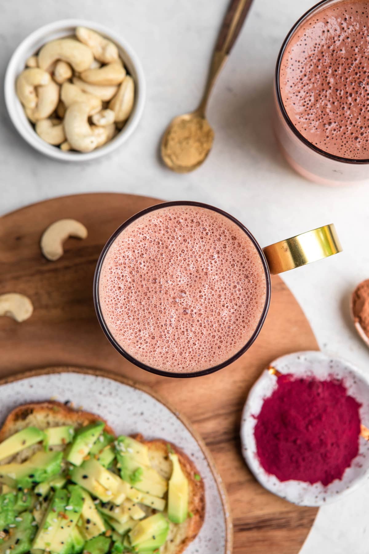 overhead shot of frothy beet latte with avocado toast