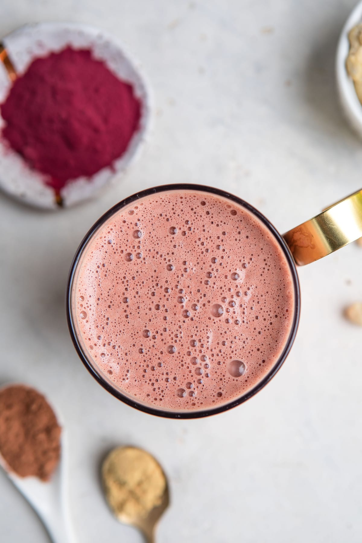 overhead shot of foamy beet latte on white background