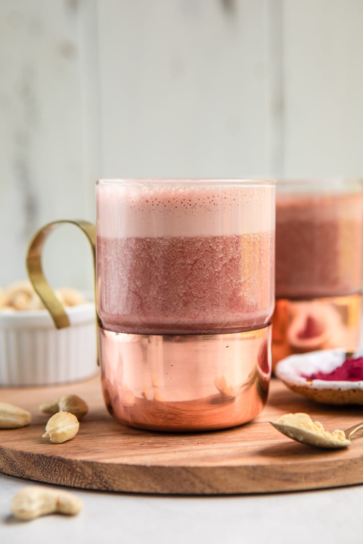 frothy pink beet latte in clear glass mug with gold handle