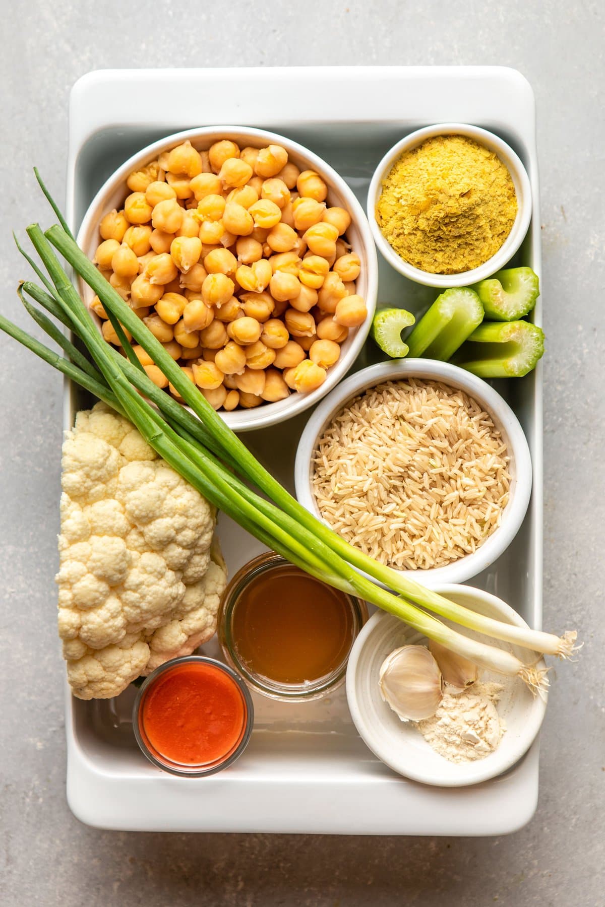 ingredients for buffalo cauliflower casserole arranged in small bowls in white casserole dish
