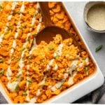 buffalo cauliflower & chickpea casserole in white casserole dish drizzled with vegan ranch