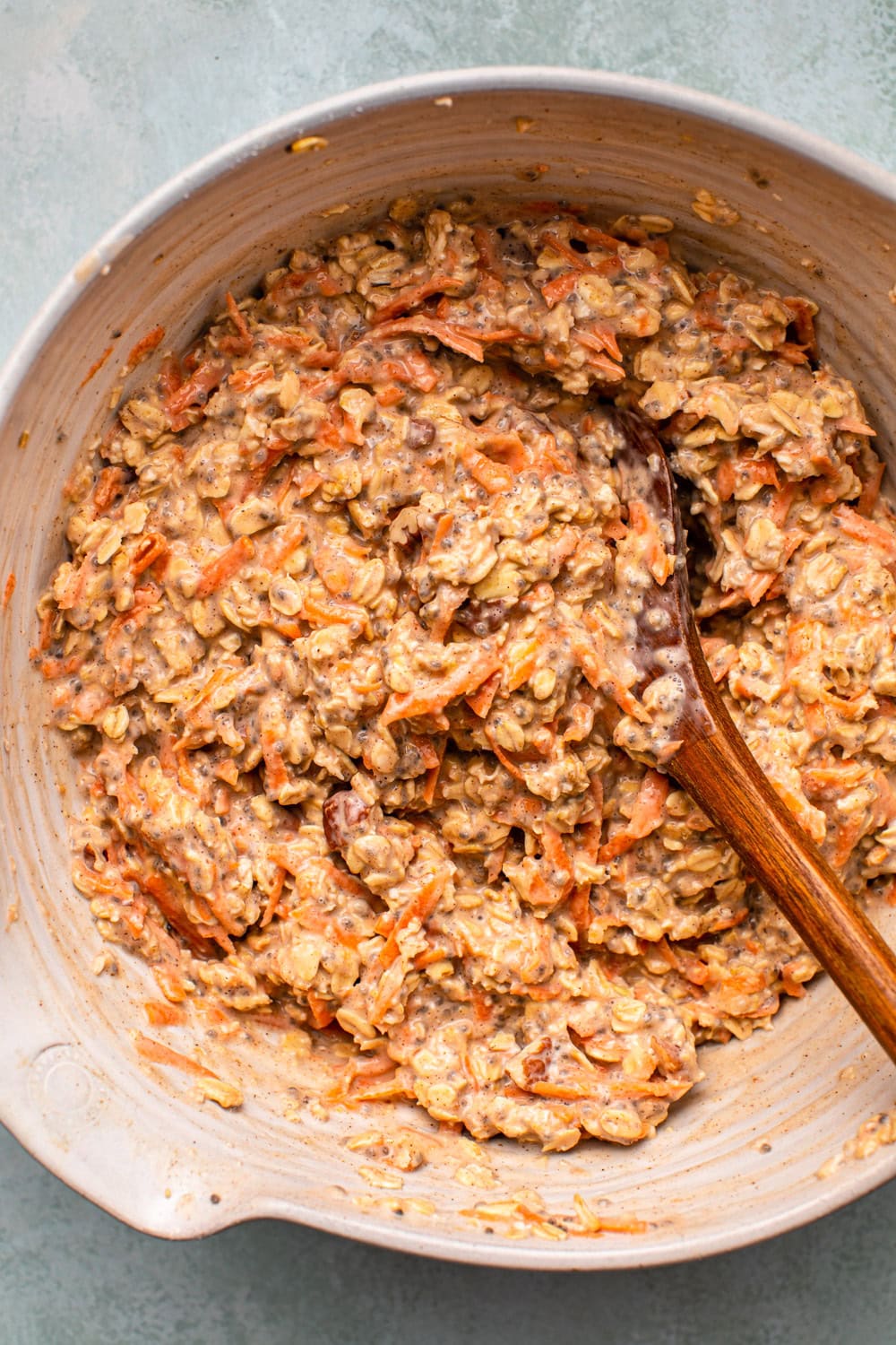 a zoomed in photo of overnight oats in a large bowl with a spoon stirring to show its texture