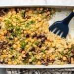 chickpea rice cassrole in white dish with spatula on marble background