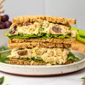 vegan chickpea salad sandwich sliced in half and stacked on white plate