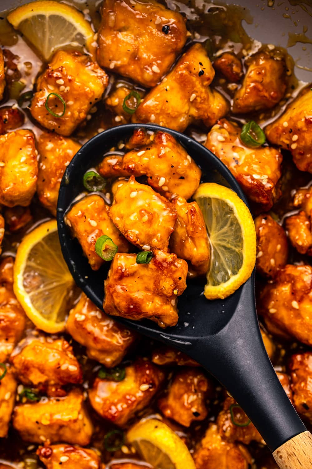 a zoomed in image of chinese lemon tofu with a large spoon scooping up a serving to showcase the texture of the lemon sauce