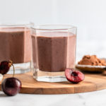two glasses of chocolate cherry almond smoothie with fresh cherries, cacao powder, and almond butter