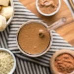 overhead shot of chocolate hemp smoothie in glass with straw on wood cutting board