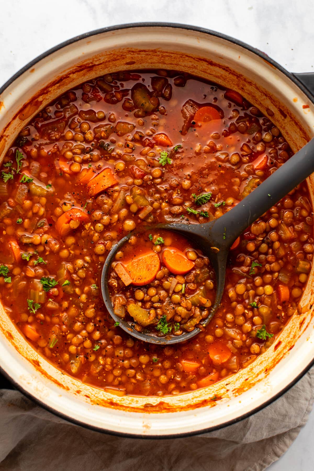 lentil soup served in a white bowl with a spoonful of it scooped up