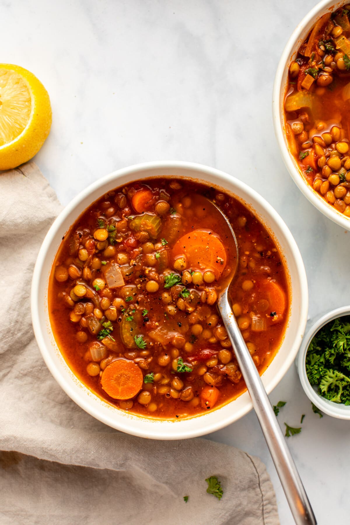 lentil soup served in a white bowl with a spoonful of it scooped up