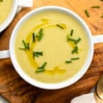 Bowl of vegan potato leek soup topped with olive oil and chives