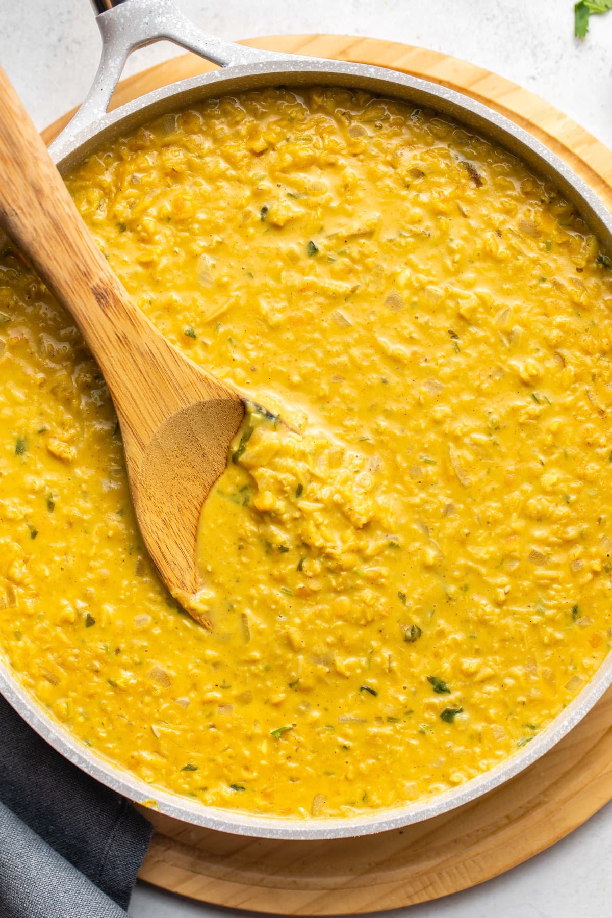 white pan of coconut curry red lentils with wooden spoon