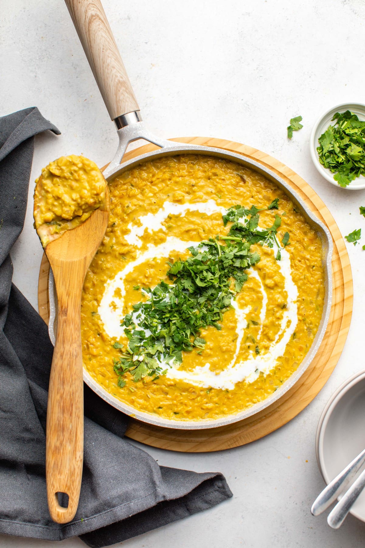 large white pot of red lentil curry topped with coconut milk and cilantro