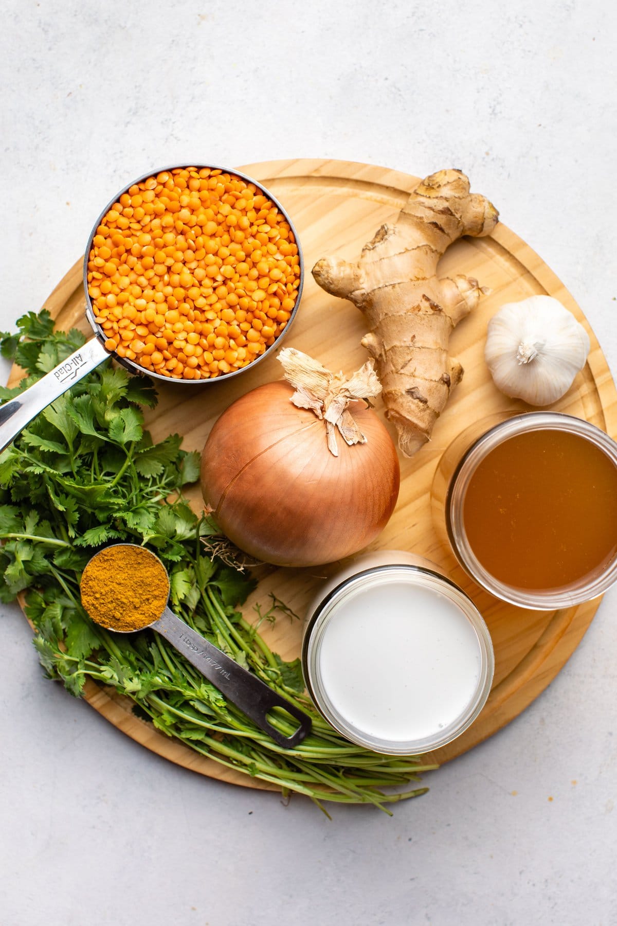 ingredients for coconut red lentil curry on round wood cutting board