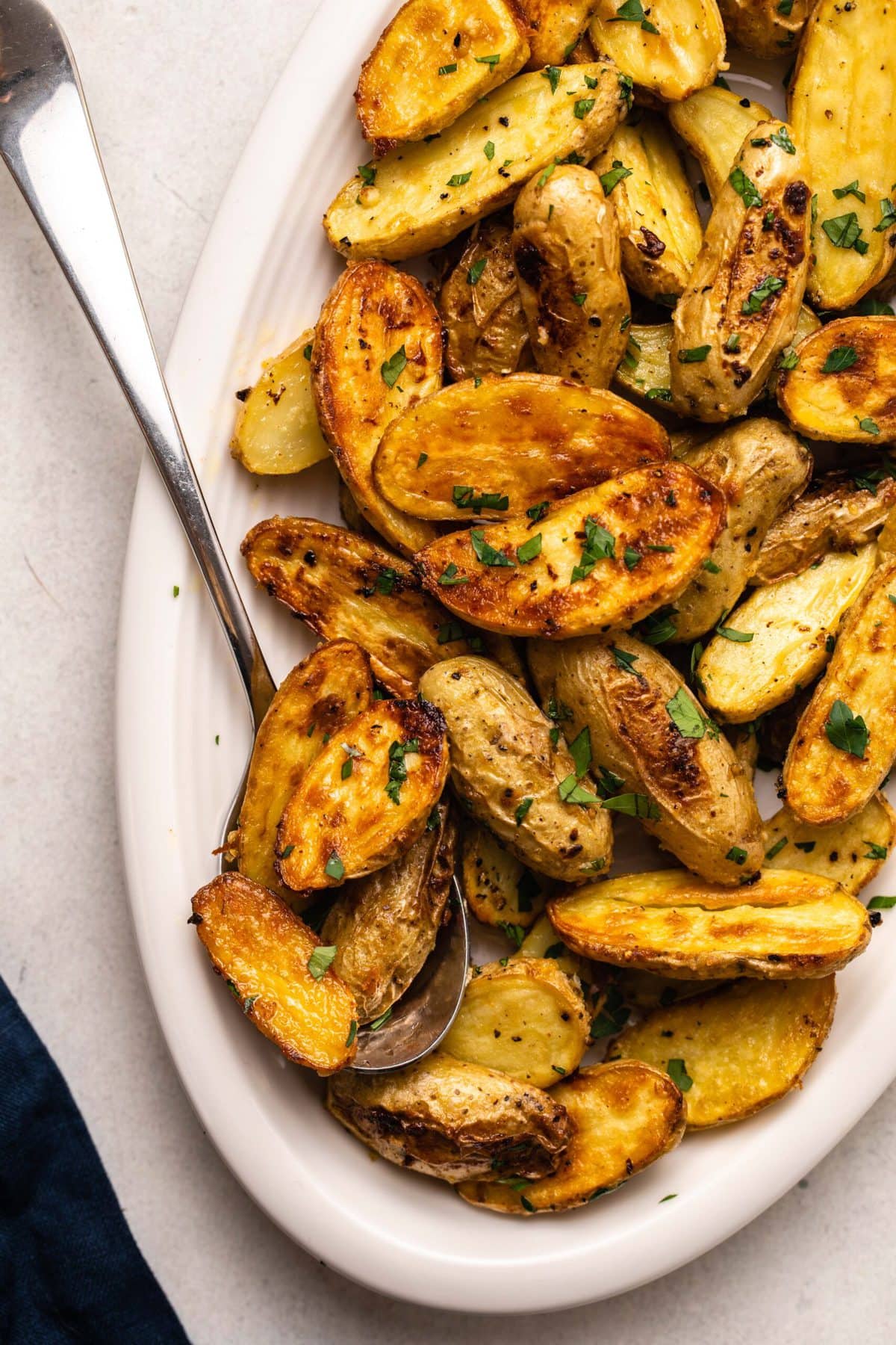 roasted potatoes topped with parsley on white serving dish on kitchen countertop