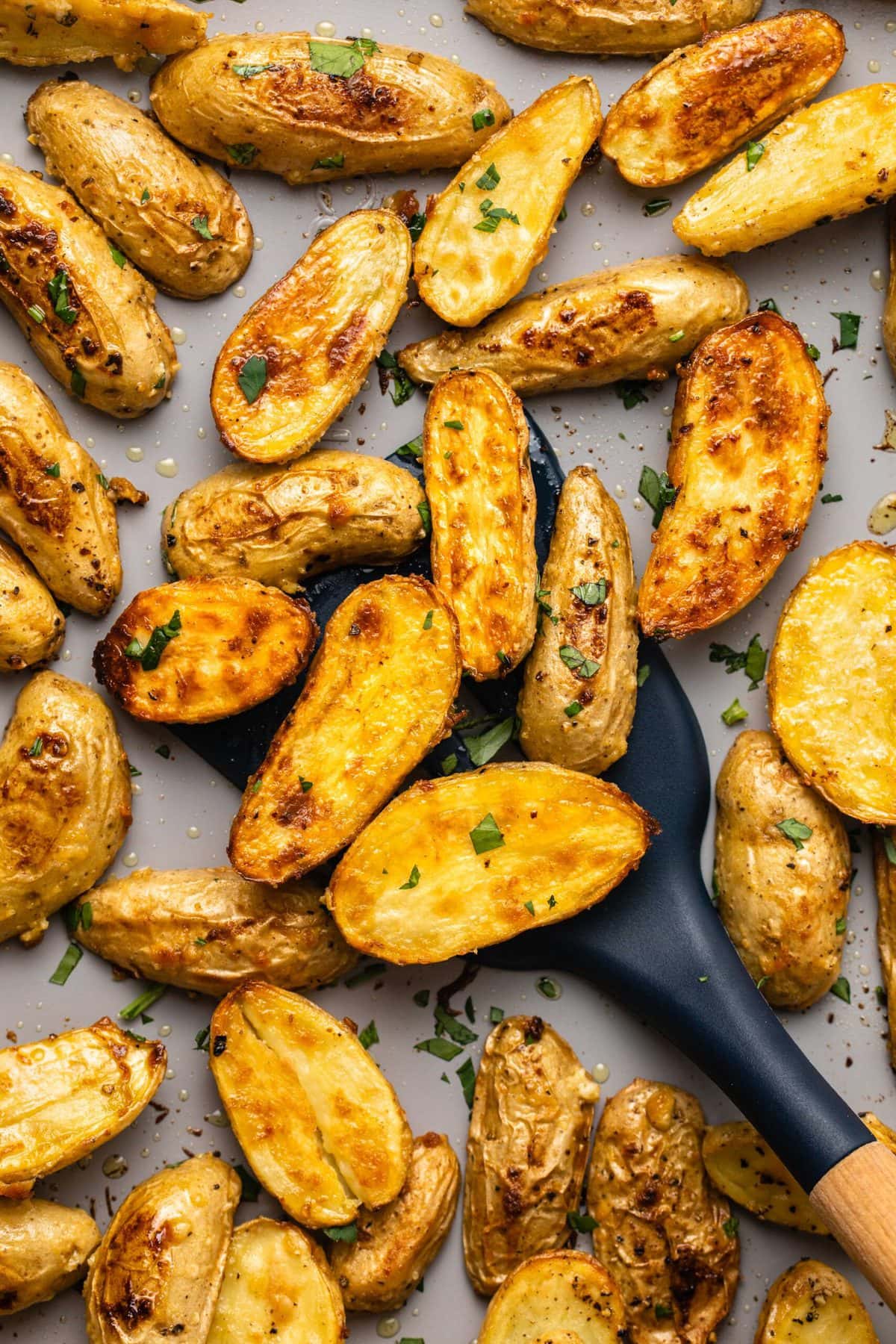 Roasted potatoes on baking sheet with spatula scooping them up
