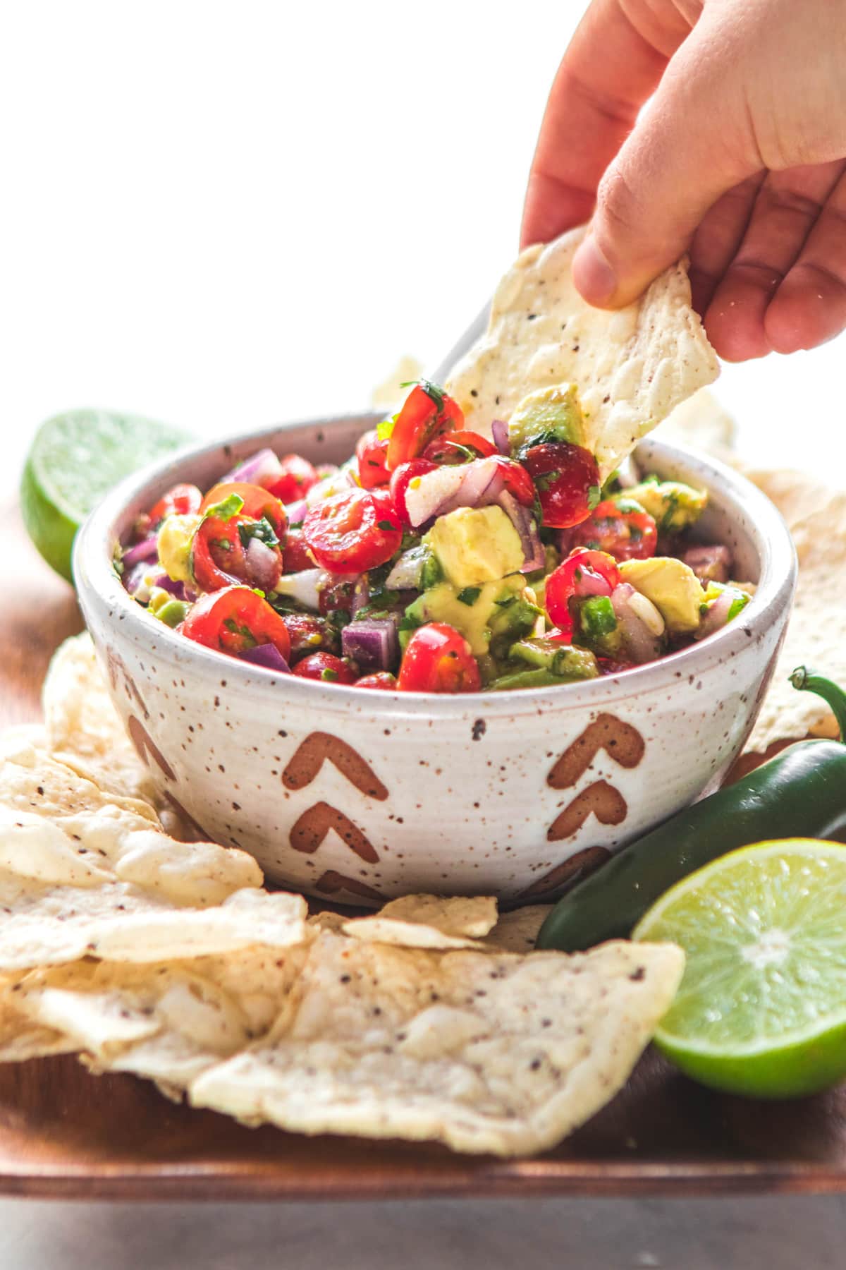 hand dipping chip into avocado salsa