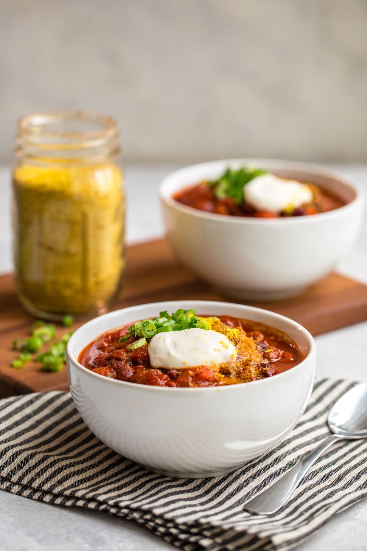 side shot of two bowls of vegan chili on wood cutting board