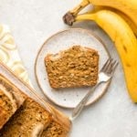 slice of vegan banana bread on white speckled plate on light gray background
