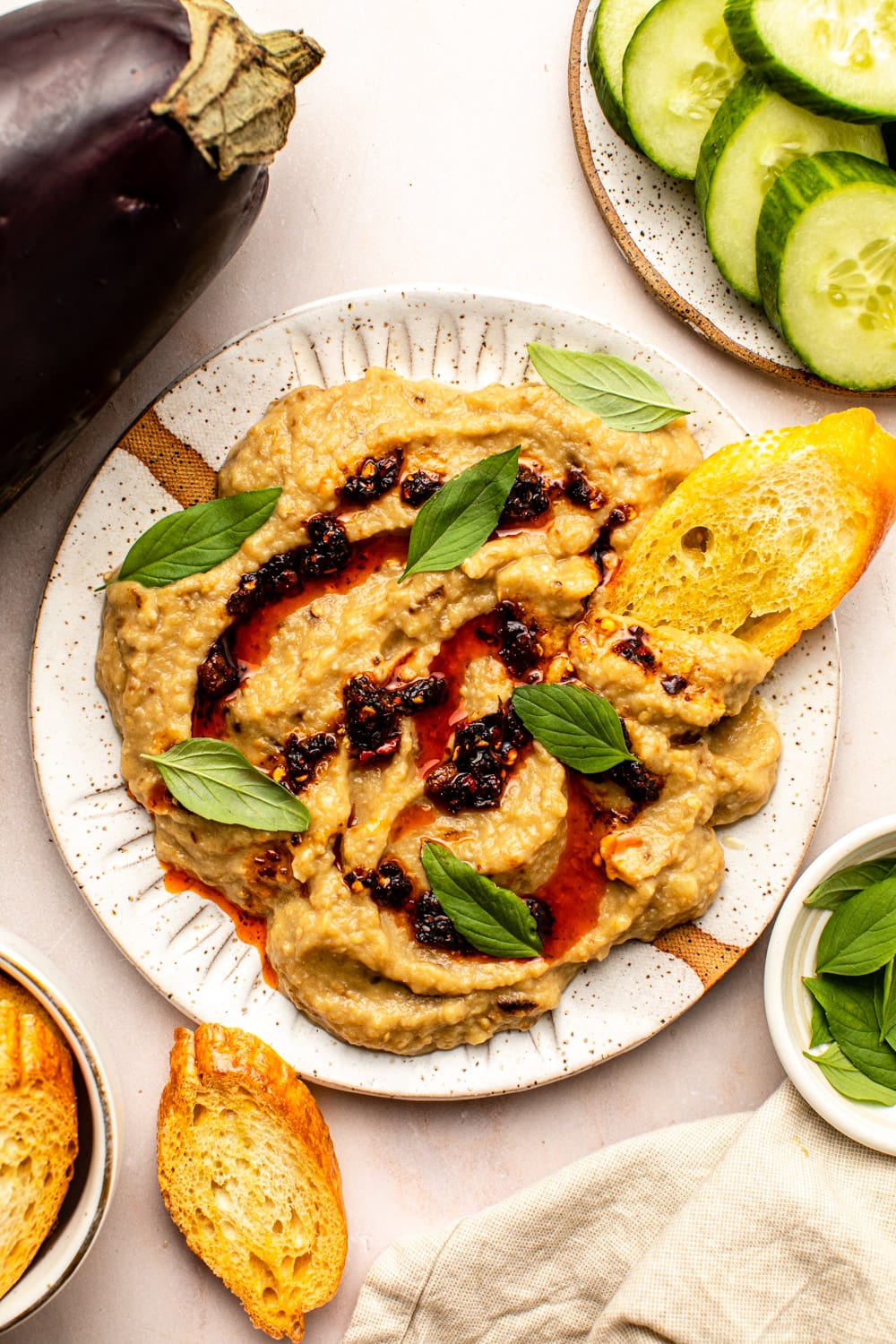 garlic miso eggplant dip served in a bowl topped with chili oil, mint leaves and toasted bread