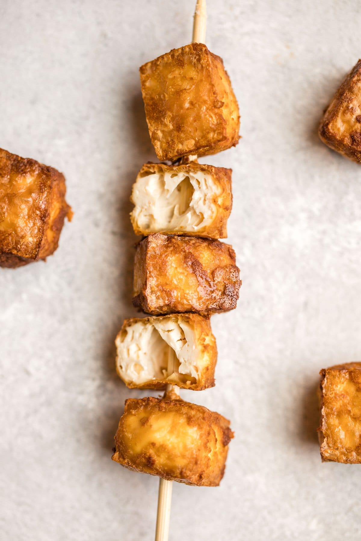 crispy tofu on skewer on grey stone background