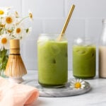 Two glasses of matcha latte with ice and gold straw