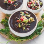 black bean soup in white bowls with salsa and cilantro