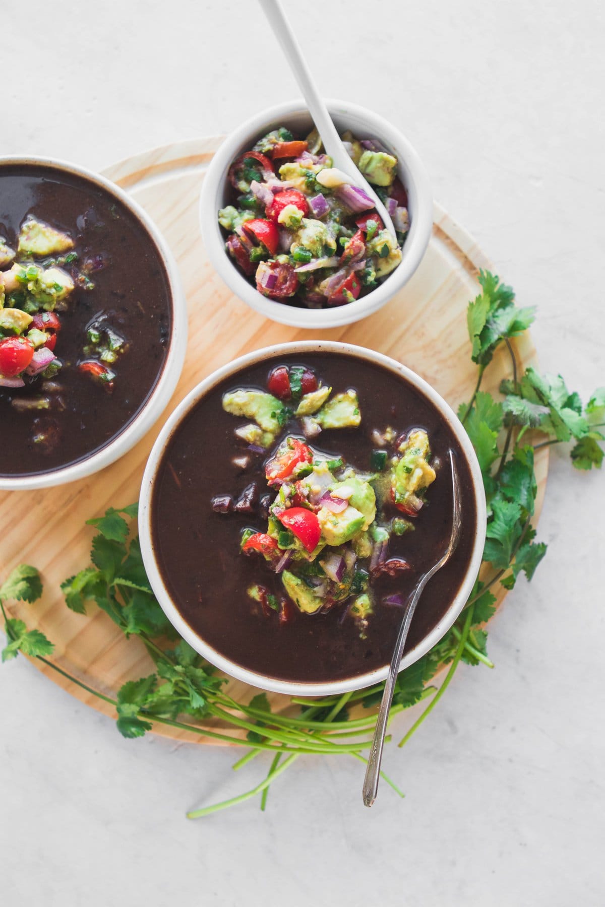 black bean soup in white bowls with salsa and cilantro