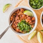 bowl of rice and beans on wood cutting board with lime