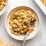 bowl of chickpea noodle casserole next to white casserole dish on marble background