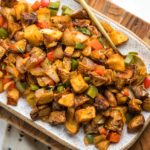 white serving platter of vegan breakfast potatoes with gold spoon