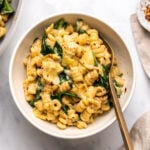 bowl of spinach artichoke pasta with gold fork
