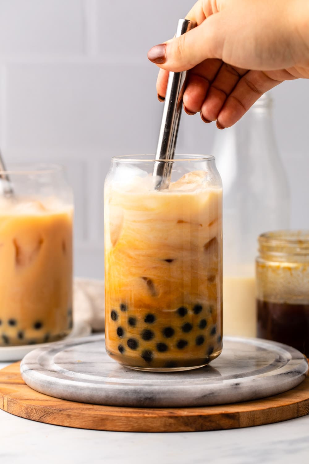 hand mixing glass of bubble tea with metal straw