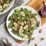 quinoa & arugula salad on white plate and wood cutting board