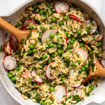 Large mixing bowl with spring orzo salad wooden serving utensils