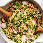 Large mixing bowl with spring orzo salad wooden serving utensils
