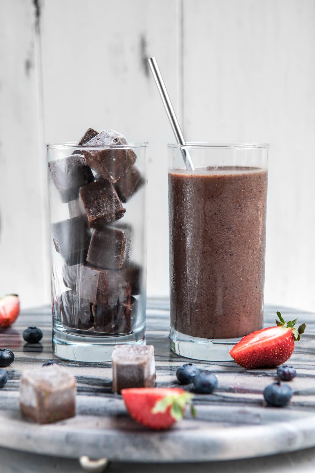 side by side glass jars, one full of unblended smoothie cubes and the other with blended cubes