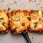 Baked tofu parmesan topped with vegan cheese and marinara sauce on baking sheet