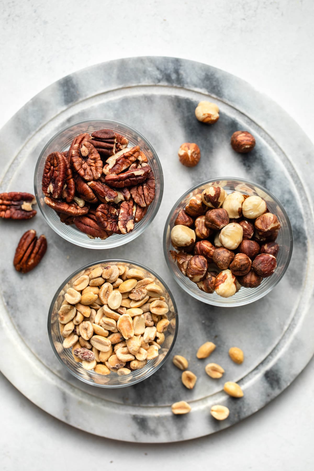 glass bowls of pecans, hazelnuts, and peanuts