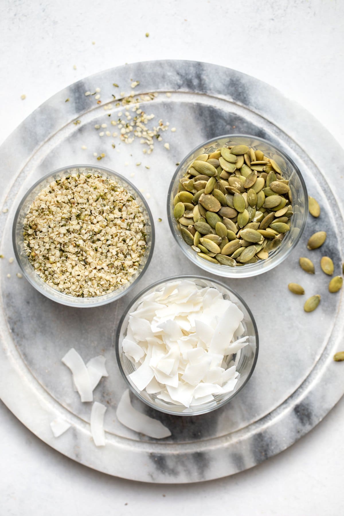 glass bowls of hemp hearts, pumpkin seeds, and coconut