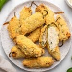Baked cornmeal-crusted jalapeño poppers arranged on a white plate on marble background