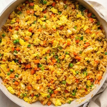 cooked vegan fried rice in large white skillet on white stone countertop