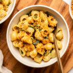 bowl of jalapeño mac and cheese topped with garlic bread crumbs on wood serving board