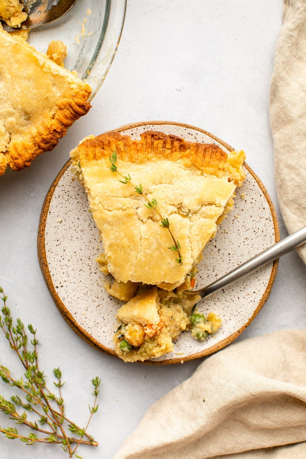 slice of chickpea pot pie topped with fresh thyme on white speckled plate