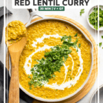 large white pot of red lentil curry topped with coconut milk and cilantro