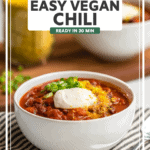 close-up photo of chili in white bowl topped with vegan sour cream, nutritional yeast, and green onions