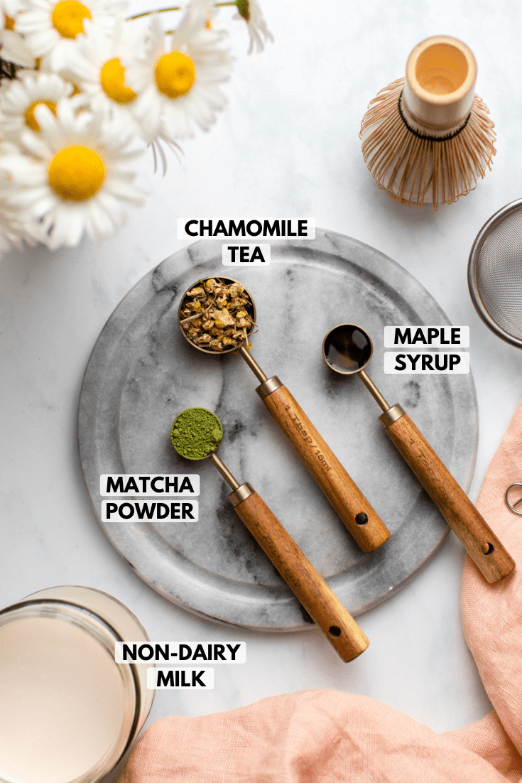 ingredients for matcha latte in gold and wooden teaspoons on marble background