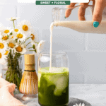hand pouring milk over chamomile and matcha mixture in glass with ice